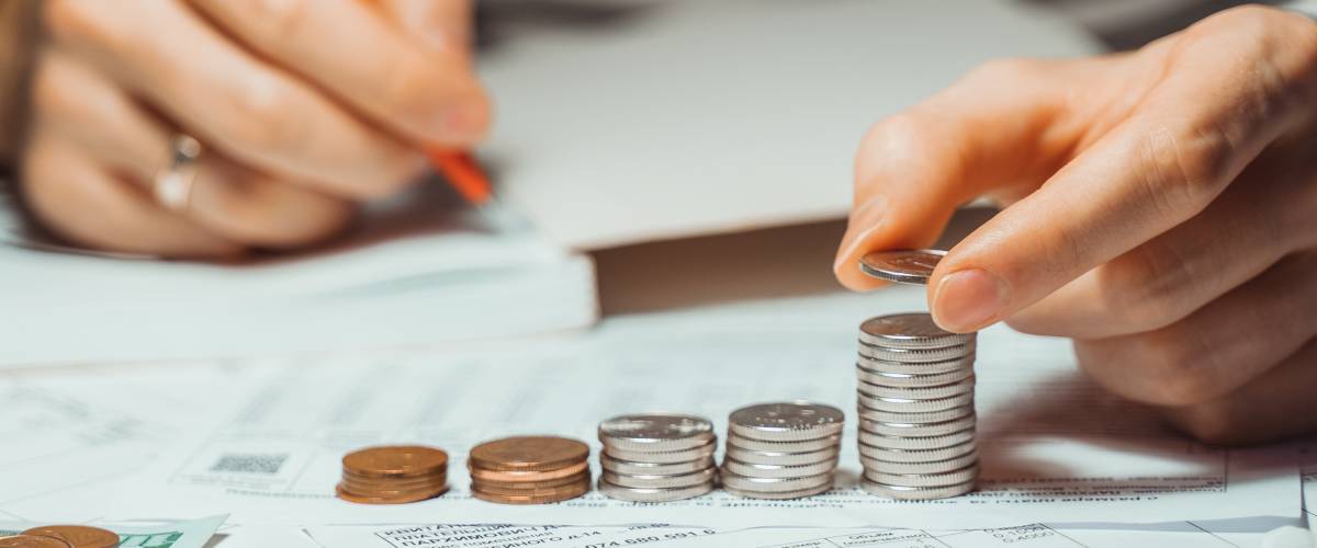Close up of man stacking coins and taking notes.