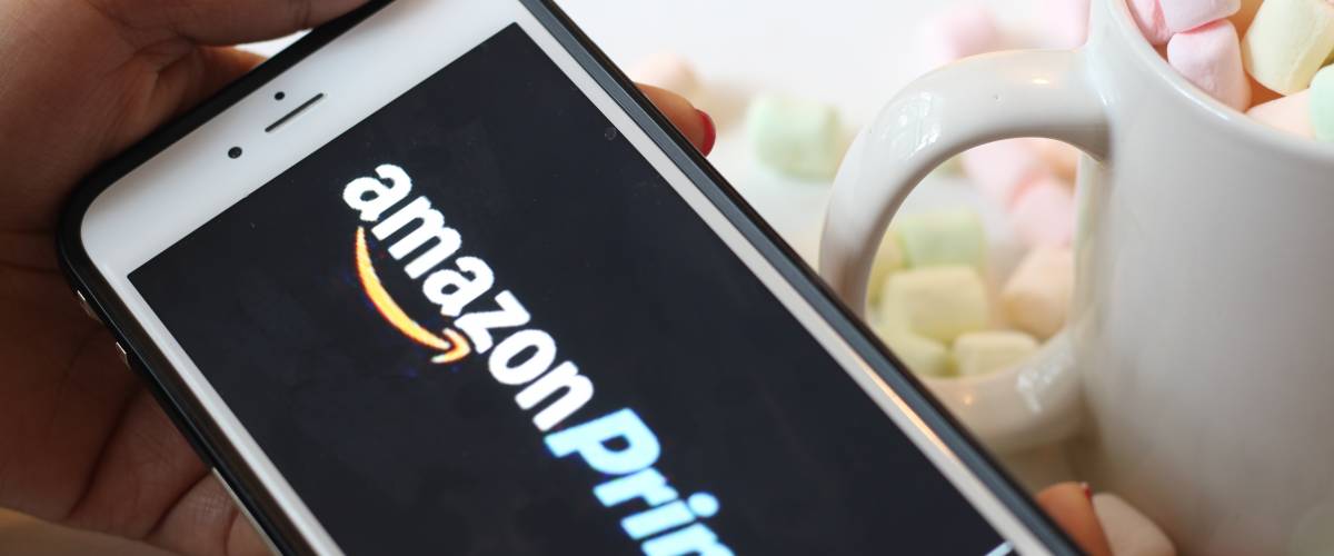 Close up of hand holding phone with Amazon Prime logo on screen.