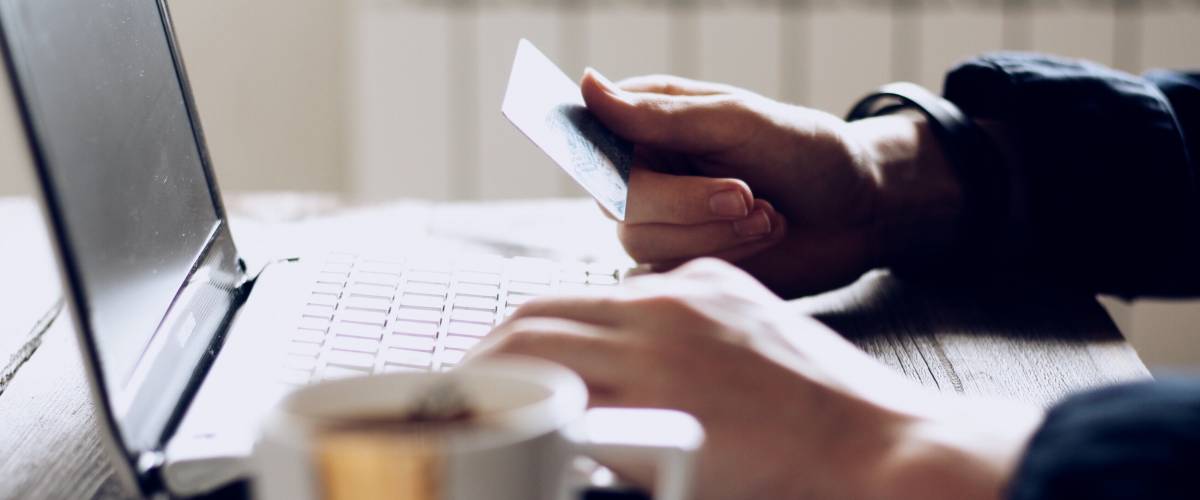 Close up of person using credit card while sitting in front of laptop.