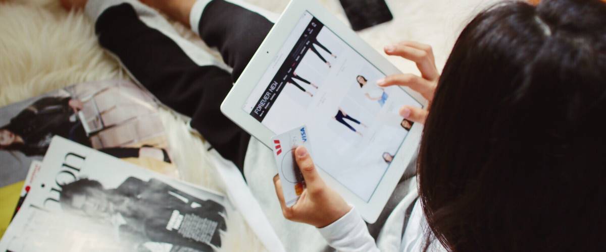 Woman seen from above using tablet to online shop for clothing.