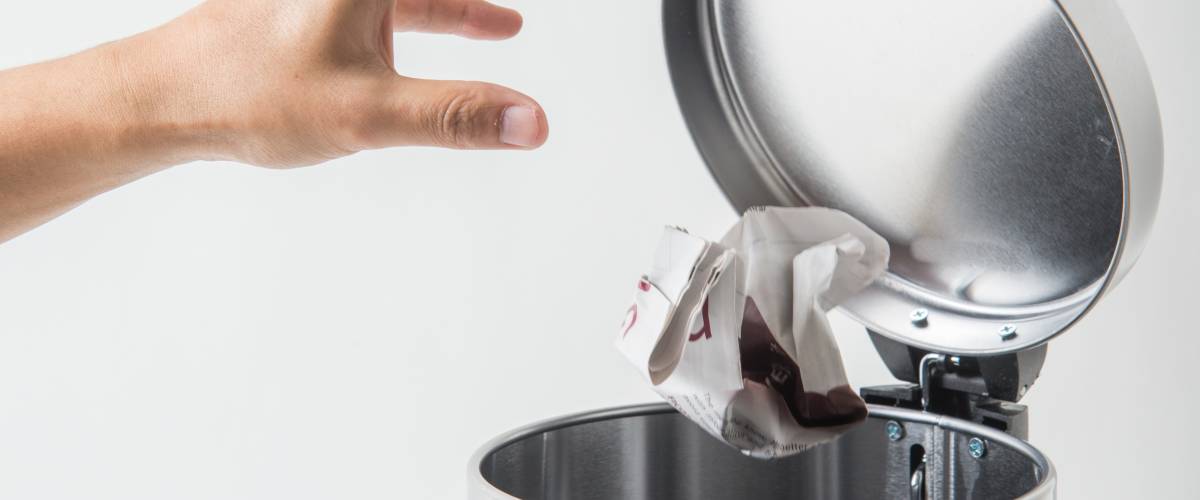 crumpled paper being tossed in a trash can