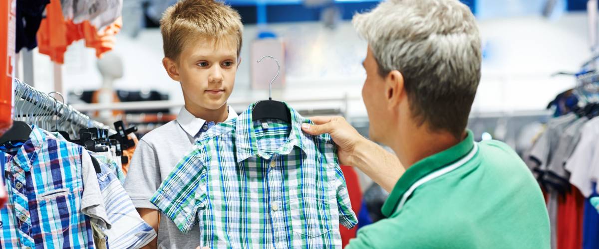 man father choosing shirt with son boy during shopping at garments shop