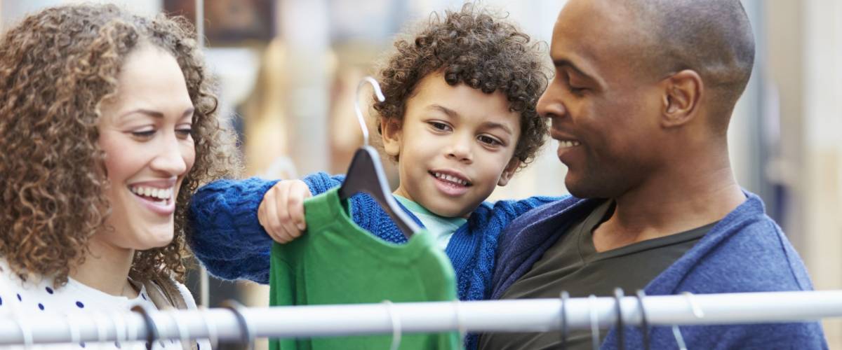 Family Looking At Clothes On Rail In Shopping Mall