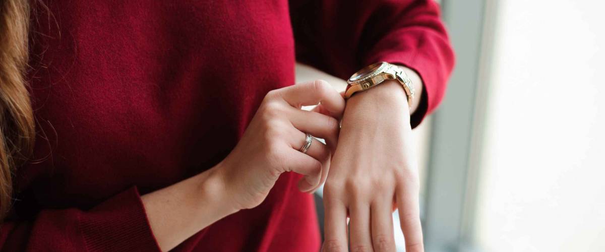Close up of woman in red sweater looking at watch on her wrist.