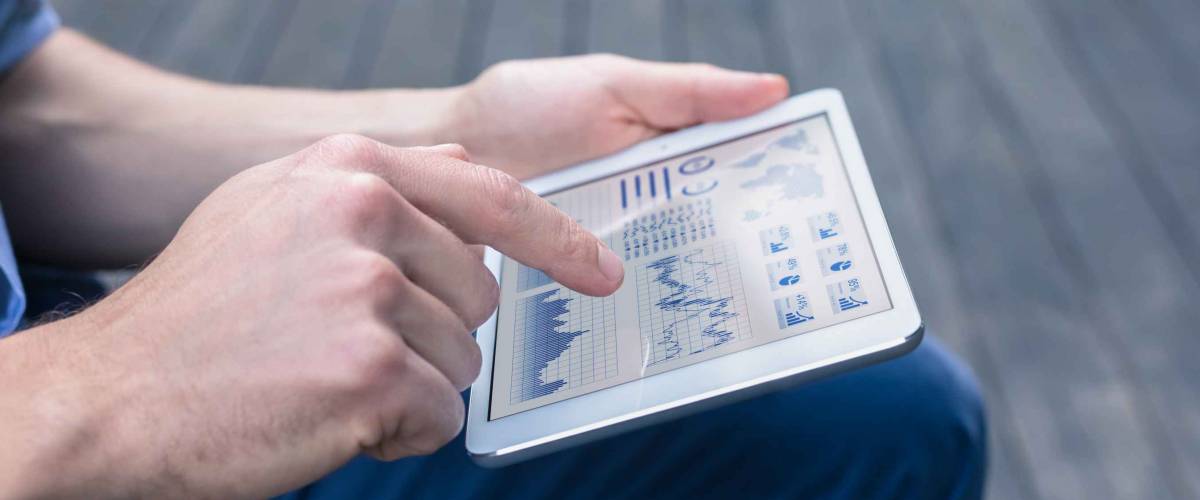 Close up of man casually looking at stock market charts on a tablet.