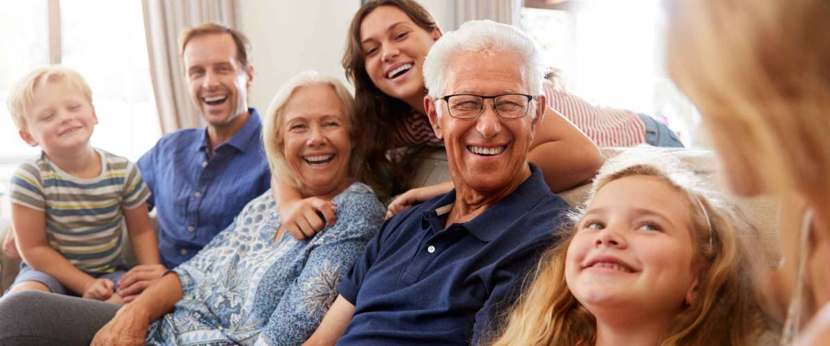 Multi-Generation Family Sitting On Sofa At Home Relaxing And Chatting