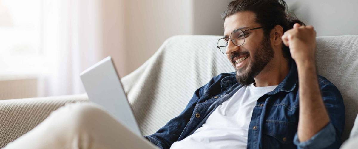 Cheerful Indian Man Celebrating Success With Digital Tablet Computer