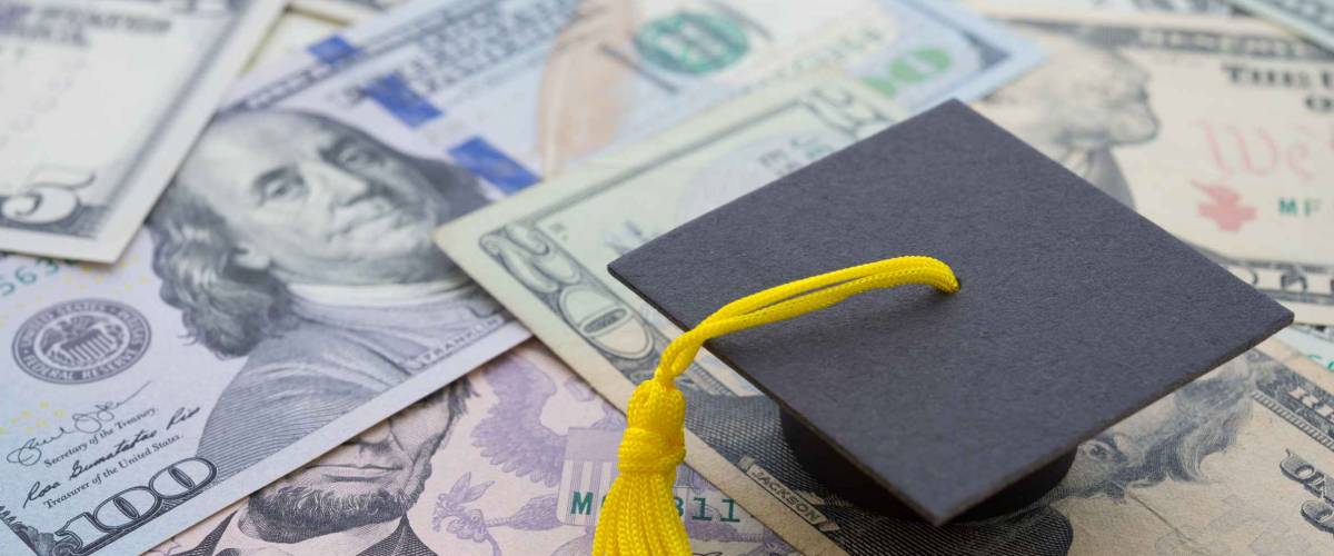 Graduation cap university or college degree on US dollars banknotes background. Education expense budget plan of money saving, loan, debt, personal loan