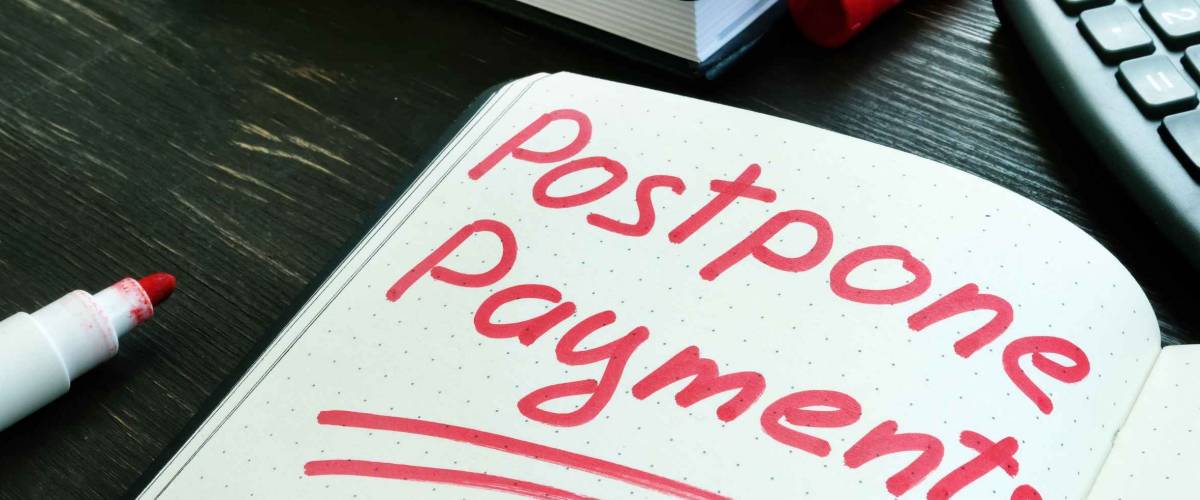 Postpone payments red memo on the page and calculator. Deferment or Forbearance concept.