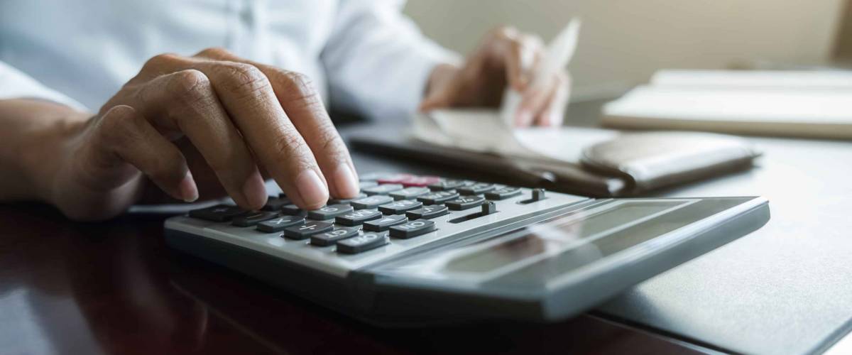 Woman using calculator to calculate bills at the table in office.