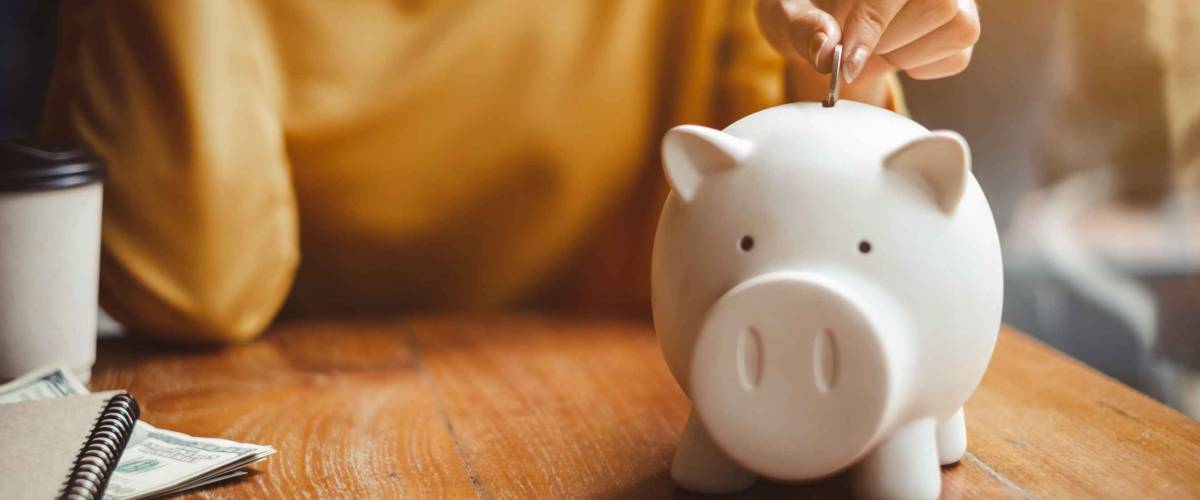 Woman putting money into piggy bank for savings.