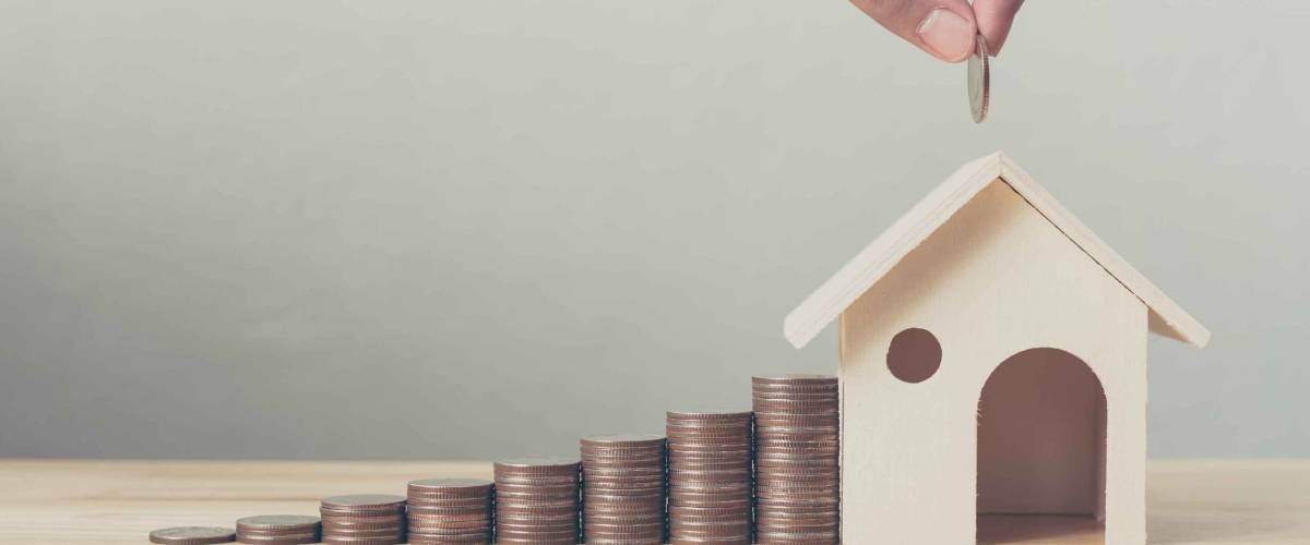 Property investment and house mortgage financial concept, Hand putting money coin stack with wooden house
