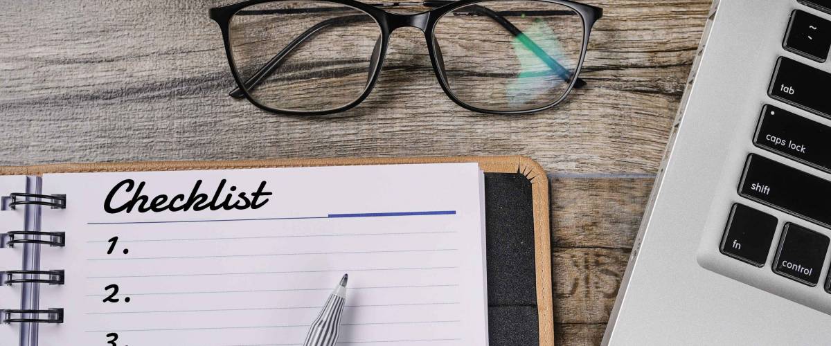 Conceptual of checklist written on wooden table with notebook and spectacle
