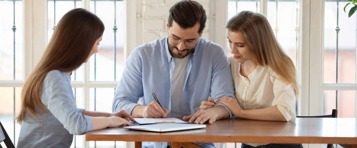 Happy young clients signing paper contract with professional broker or realtor,.