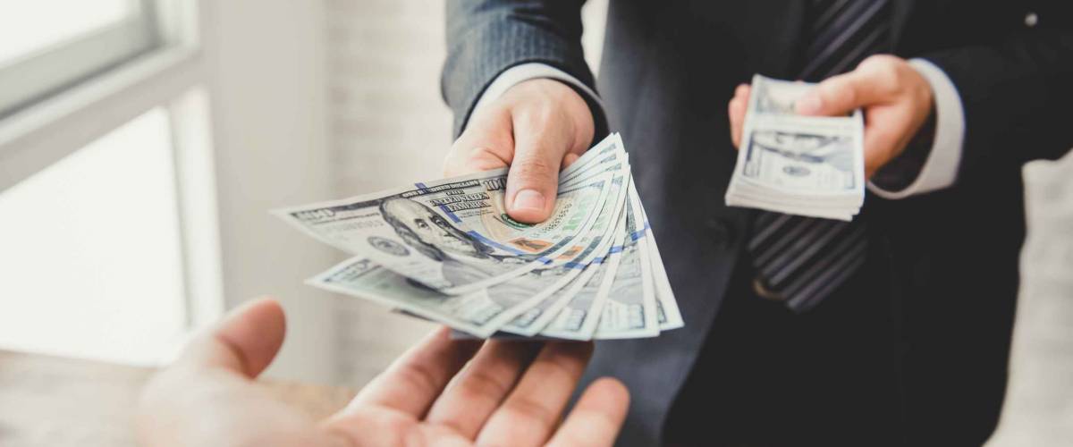 Close up of two men's hands, one passing over cash.