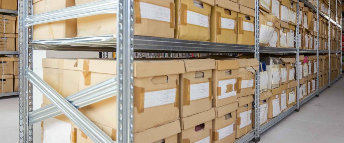 Stacks of files and paperwork placed in bookshelves with folders and documents in cardboard box archive, storage room.