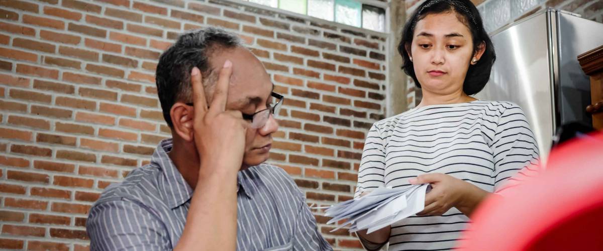 Woman showing distressed man pile of bills.