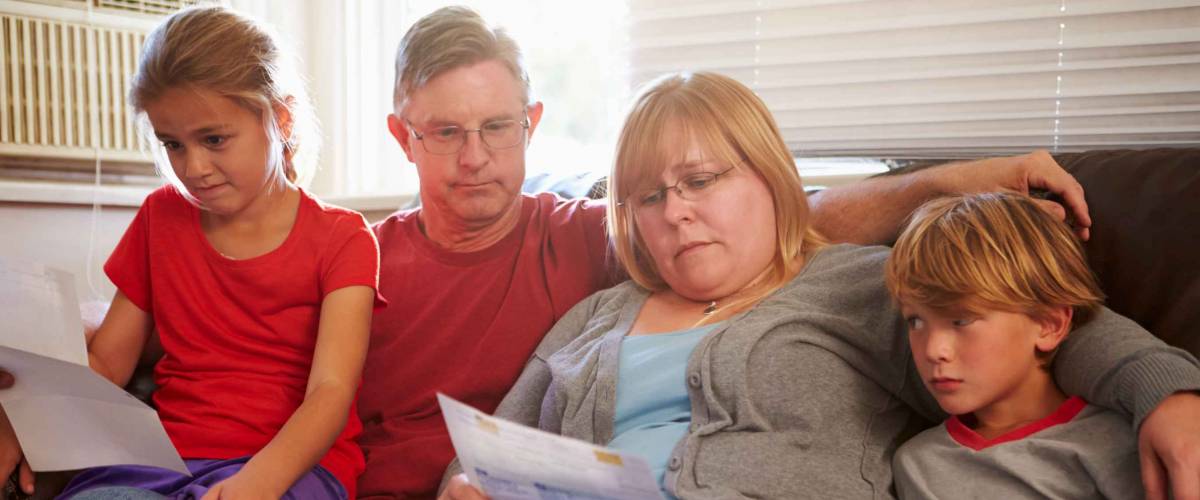 Unhappy Family Sitting On Sofa Looking At Bills