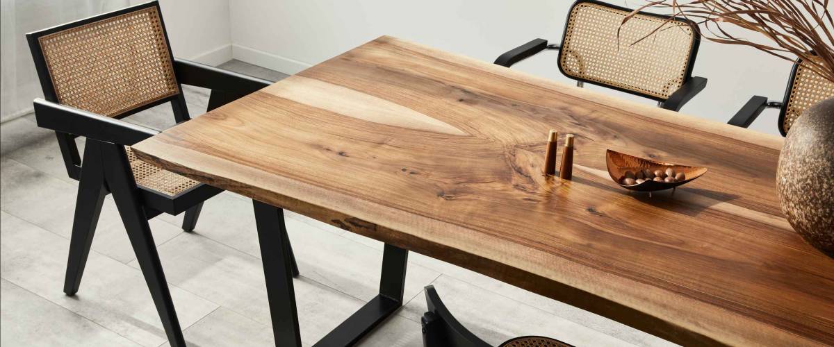 Interior design of stylish dining room interior with family wooden table, modern chairs, plate with nuts, salt and pepper shakers. Concrete floor. White wall. Template.