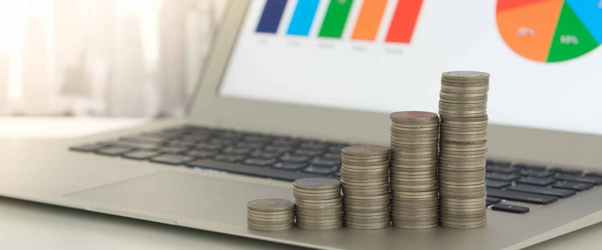 Grow up coins stack with business and finance graph screen on laptop computer on desk of investor adviser. Concept of financial and investment growth.