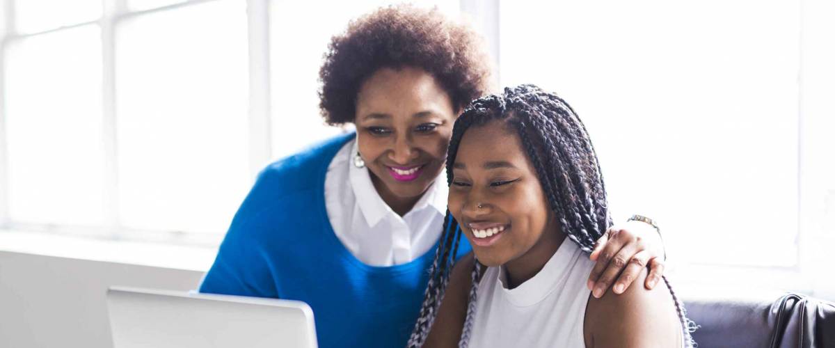 A Mother And Teenage Daughter Looking At Laptop Together