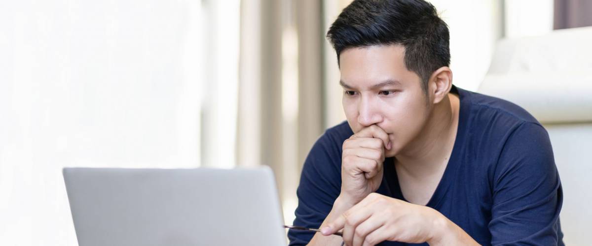 Seriously confident asian young freelancer in smart casual working and concentrated on laptop