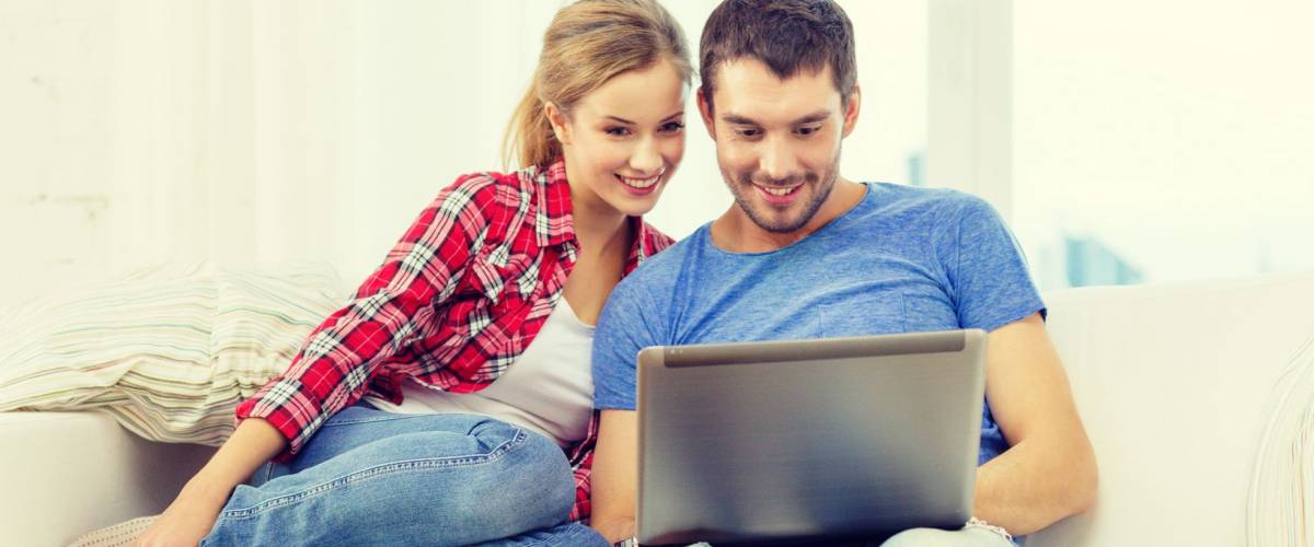 home, technology and relationships concept - smiling couple with laptop computer at home