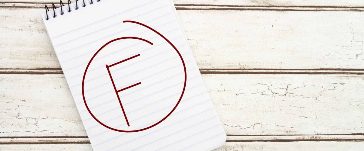 Getting a Poor Grade, A spiral Notepad that has the word F in a circle over a distressed wood background