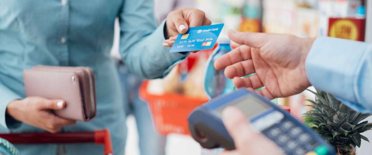 Woman at the supermarket checkout, she is paying using a credit card, shopping and retail concept