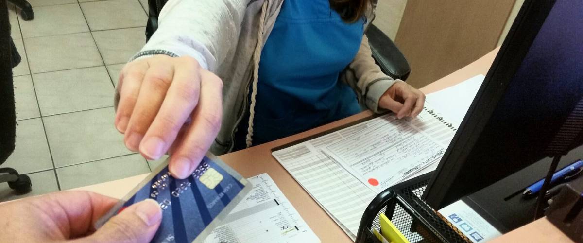 Close up of hand passing over card with a chip to a receptionist at a medical centre in scrubs.