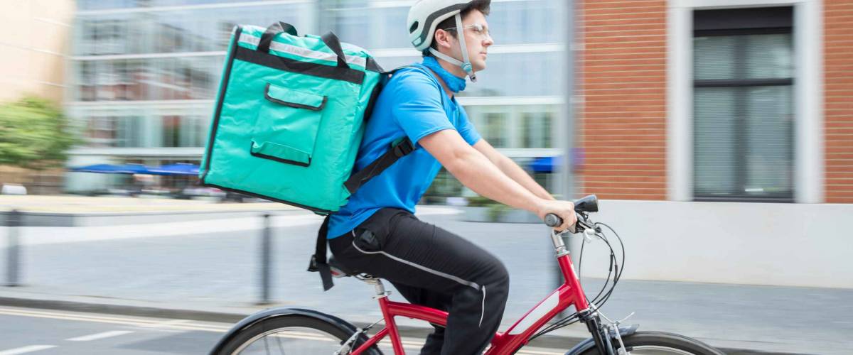Courier On Bicycle Delivering Food In City