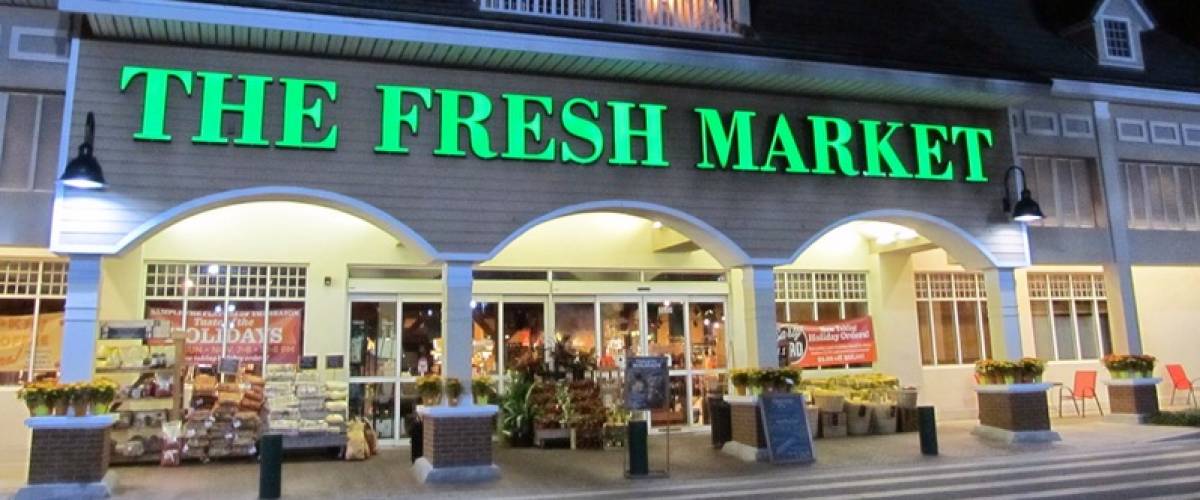 Storefront of the Fresh Market store at night.