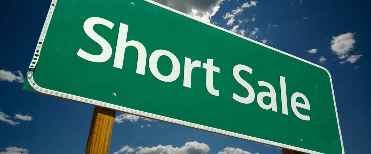 Short Sale Green Road Sign on Dramatic Blue Sky with Clouds.