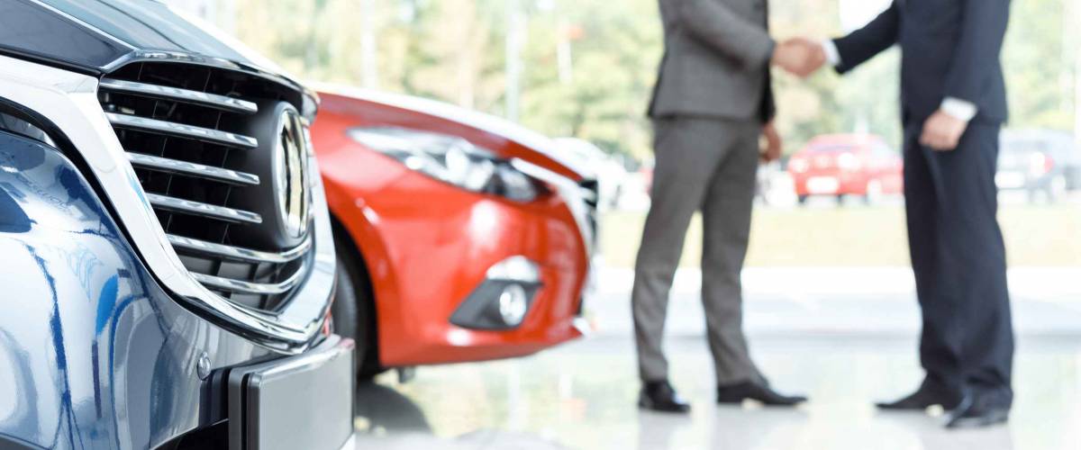 Closing the deal. Selective focus on the car customer shaking hands with dealer on the background