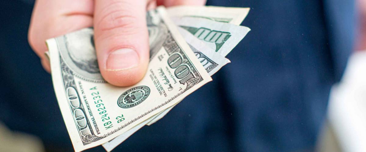 the hand holds out several hundred dollar bills folded in half. High quality photo