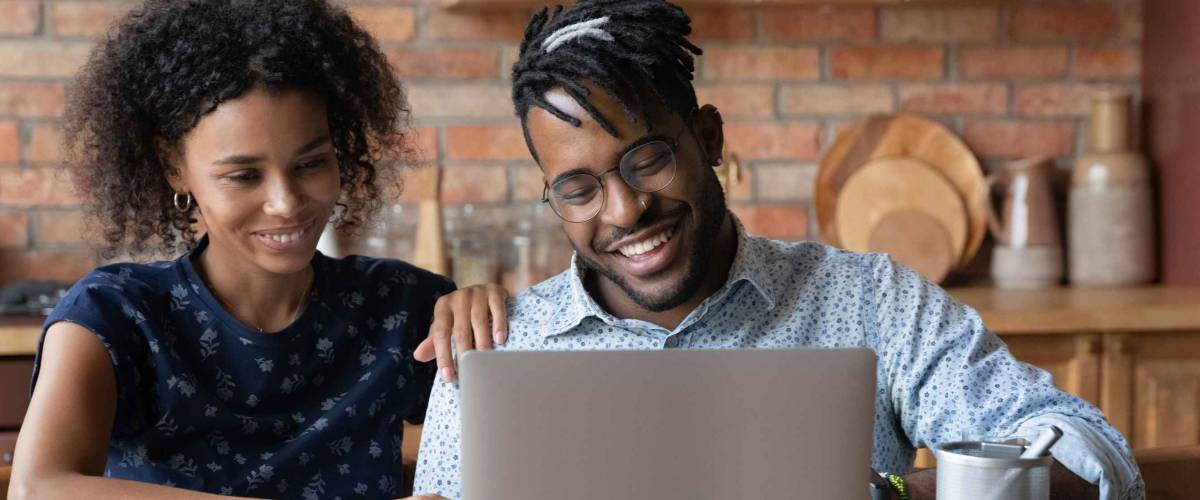 Happy african american family couple sit at home office shopping for a low mortgage rate.