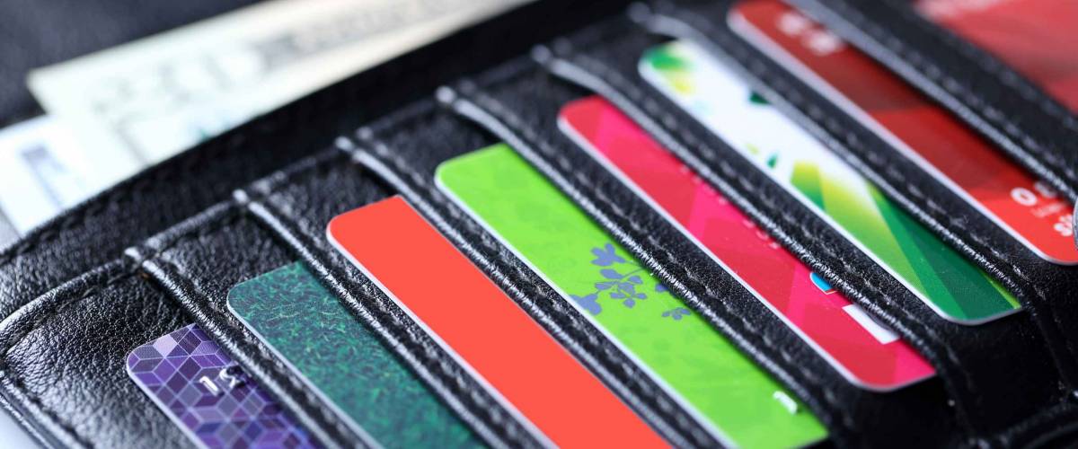 Black leather wallet with colourful credit cards and money, close up