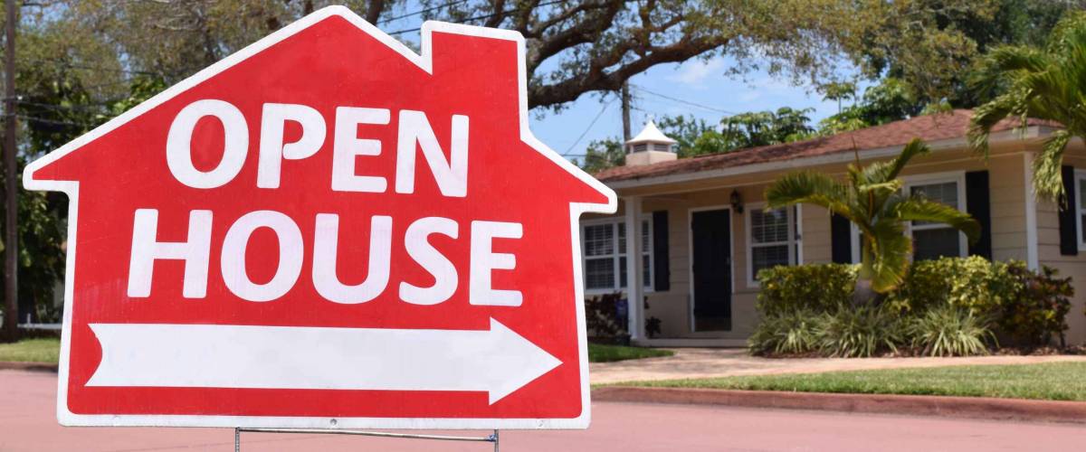 Bright red open house real estate sign in nice suburban neighborhood, sunny day.