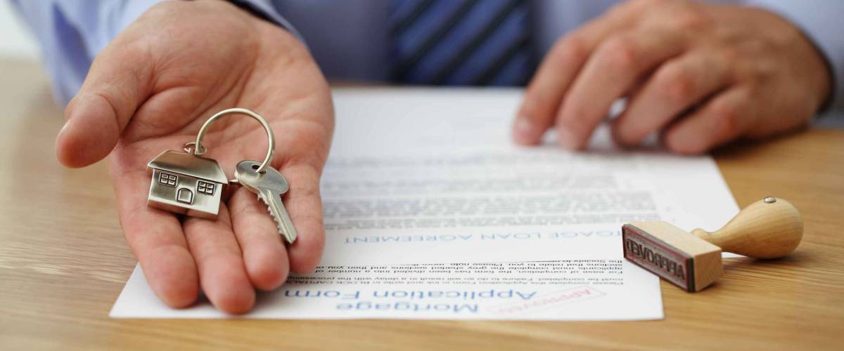 Real estate agent handing over house keys with approved mortgage application form
