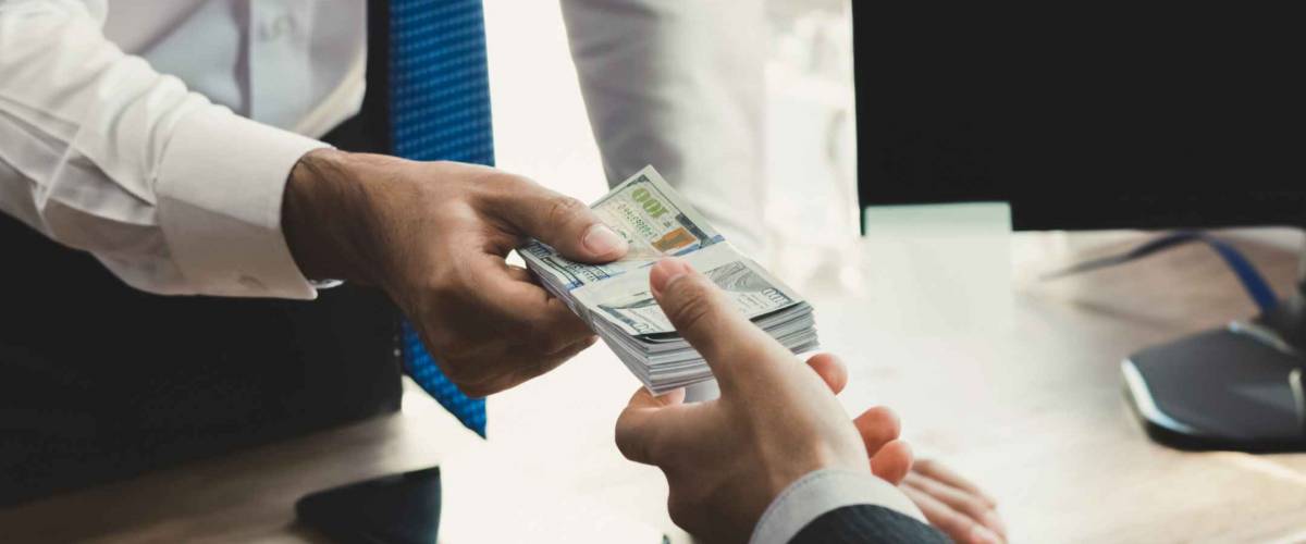 Businessman receiving money from his partner at working desk in the office - loan, bribery and corruption concepts