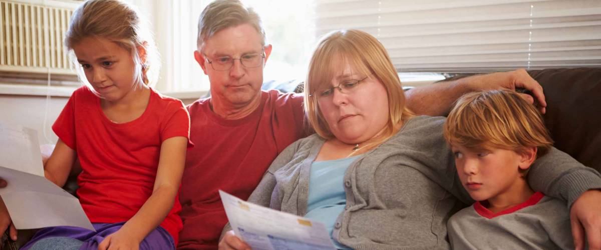 Unhappy Family Sitting On Sofa Looking At Bills