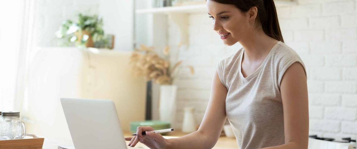 Happy young attractive woman using calculator and laptop for finding and calculating mortgage rates.