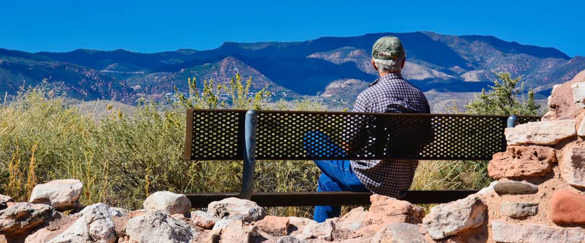 View from behind of a man sitting on metal bench enjoying the scenic view and mountains in the distance on a sunny day in Arizona - The great outdoors *nominated*