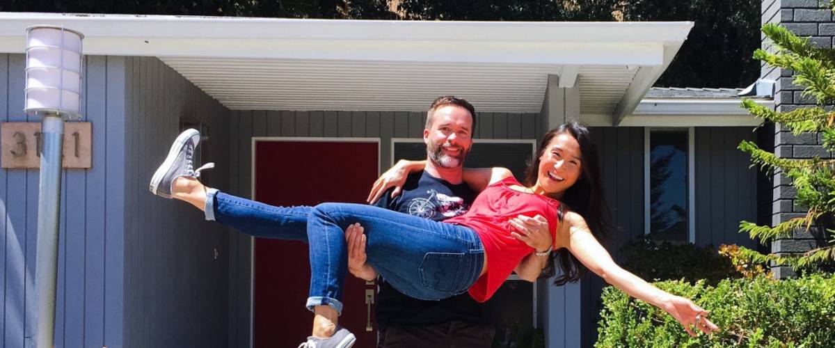 Husband and wife celebrate in front of their new home.