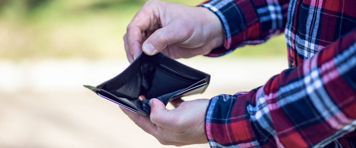 Man in plaid shirt showing his empty wallet