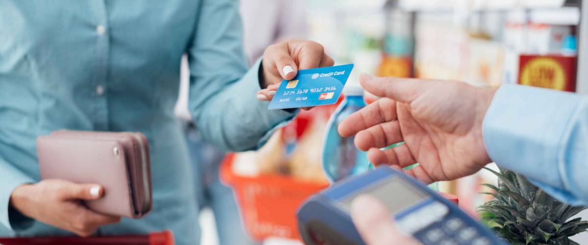 Woman at the supermarket checkout, she is paying using a credit card, shopping and retail concept