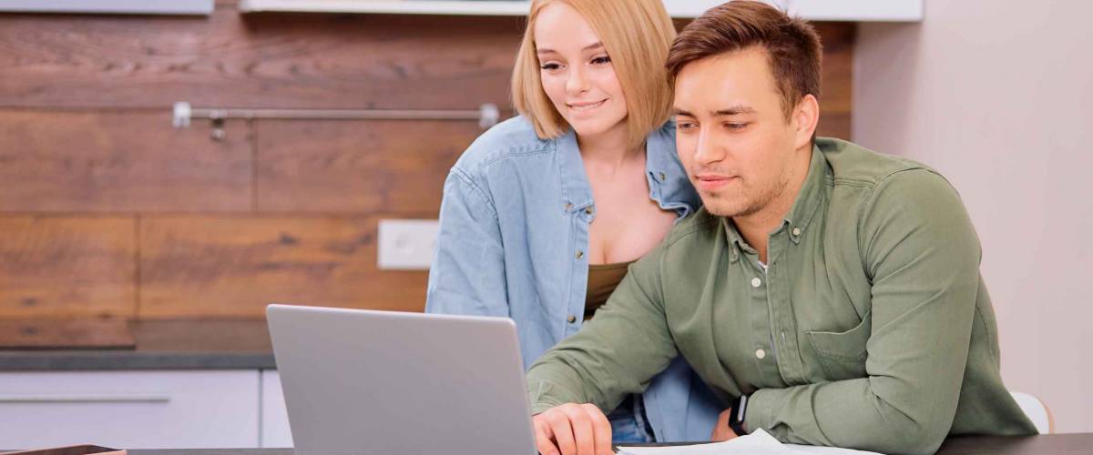 young caucasian man and woman roommates or married couple checking rent or domestic bills to pay online, planning budget or analyzing financial expenses together at home