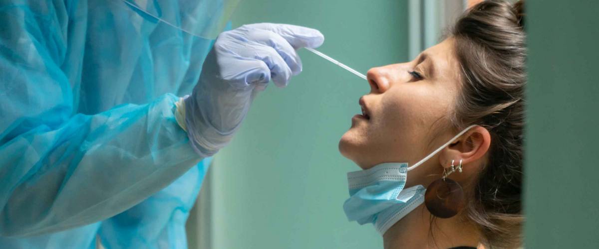 Healthcare worker with protective equipment performs coronavirus swab on Caucasian girl.Nose swab for Covid-19.