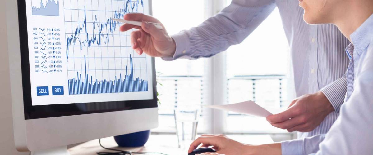 Team of traders working with foreign exchange trading charts and graphs on computer screen.