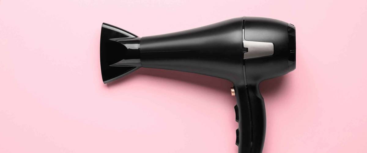 Modern hair dryer on color background